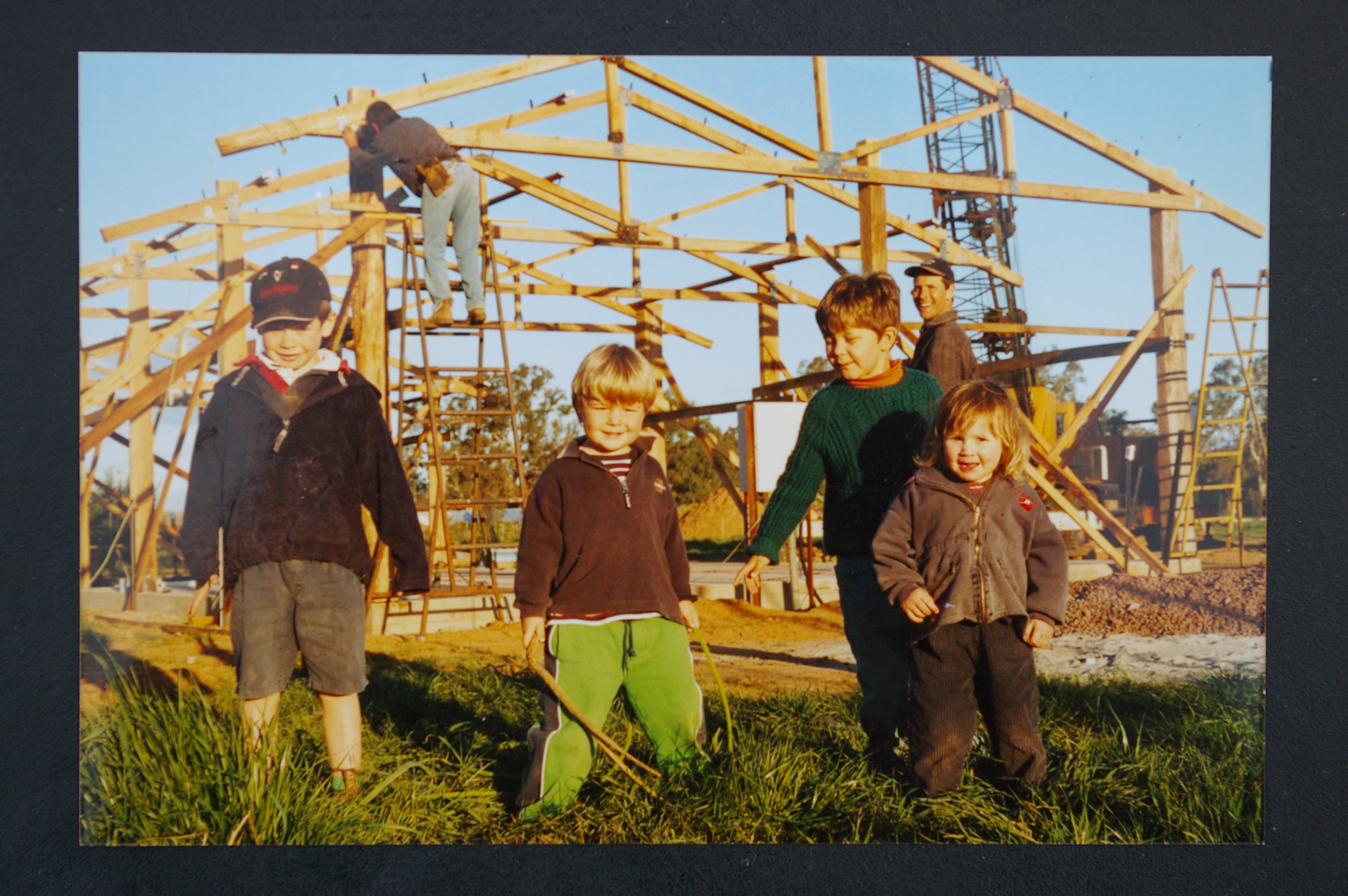 Farm building under construction, Aug 2003. Trevor Northey checking the frame with Bill Crocker’s restored 1946 Blitz gantry crane placing the truss. Felix and Grace, with cousins Ned and Joey, are in the foreground, with David behind.